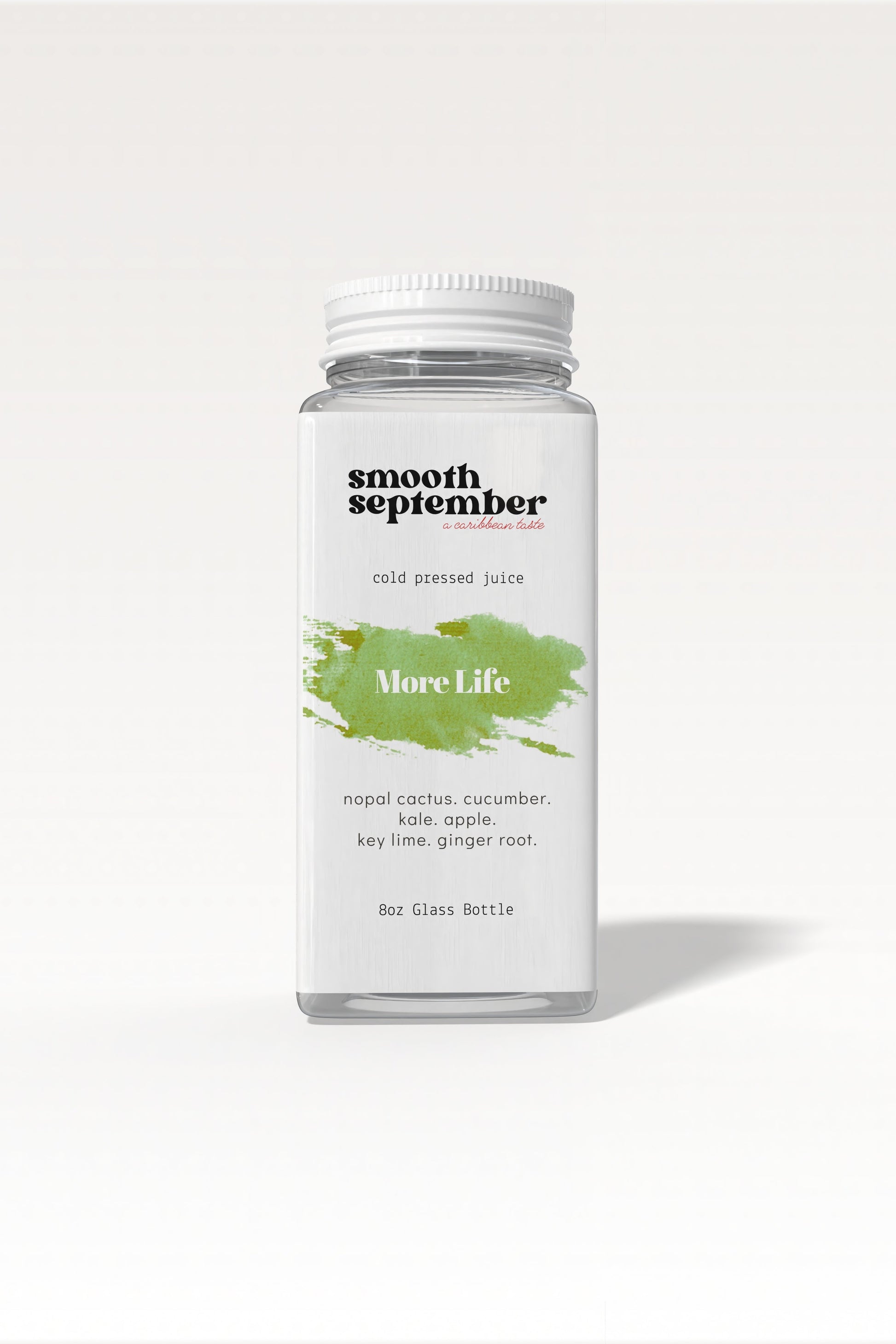A glass bottle of More Life cold-pressed green juice with a vibrant green hue, shown next to fresh ingredients like kale, apple, and cucumber.